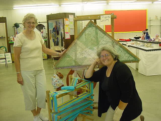 Two women posing in front of triangle loom