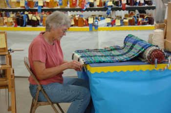 Weaver tying the fringe on a rag rug.