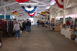 Inside barn, vendors on both sides, colorful banners on rafters.