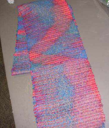 Woven scarf with splotches of pink and blue due the color of the yarns.
